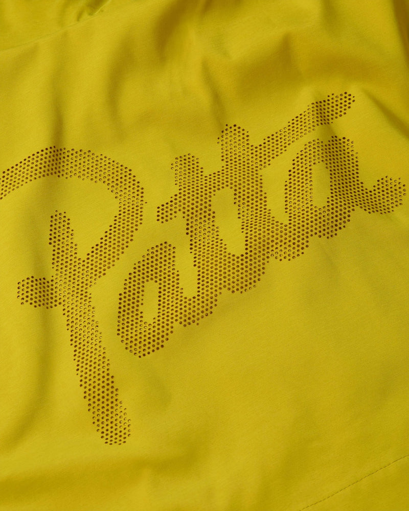 Close-up of the perforated Patta script logo on the yellow Nike x Patta Running Team track jacket.