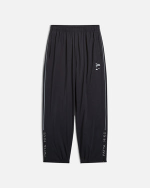 Front view of black Nike x Patta Running Team track pants with reflective side piping.