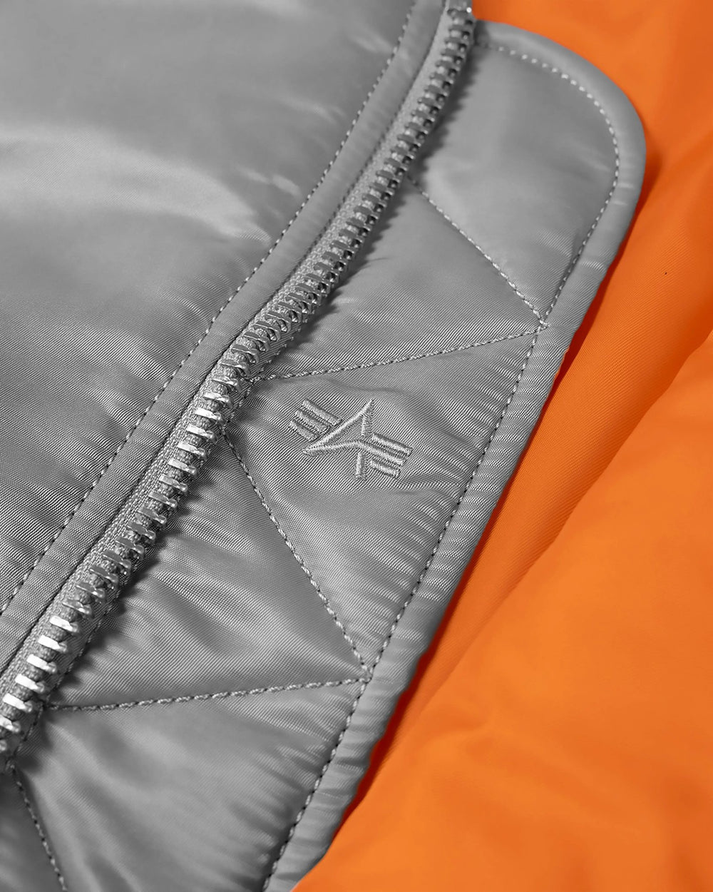 Silver nylon storm flap and zipper detail on the Patta x Alpha Industries MA-1 Celebration Jacket.