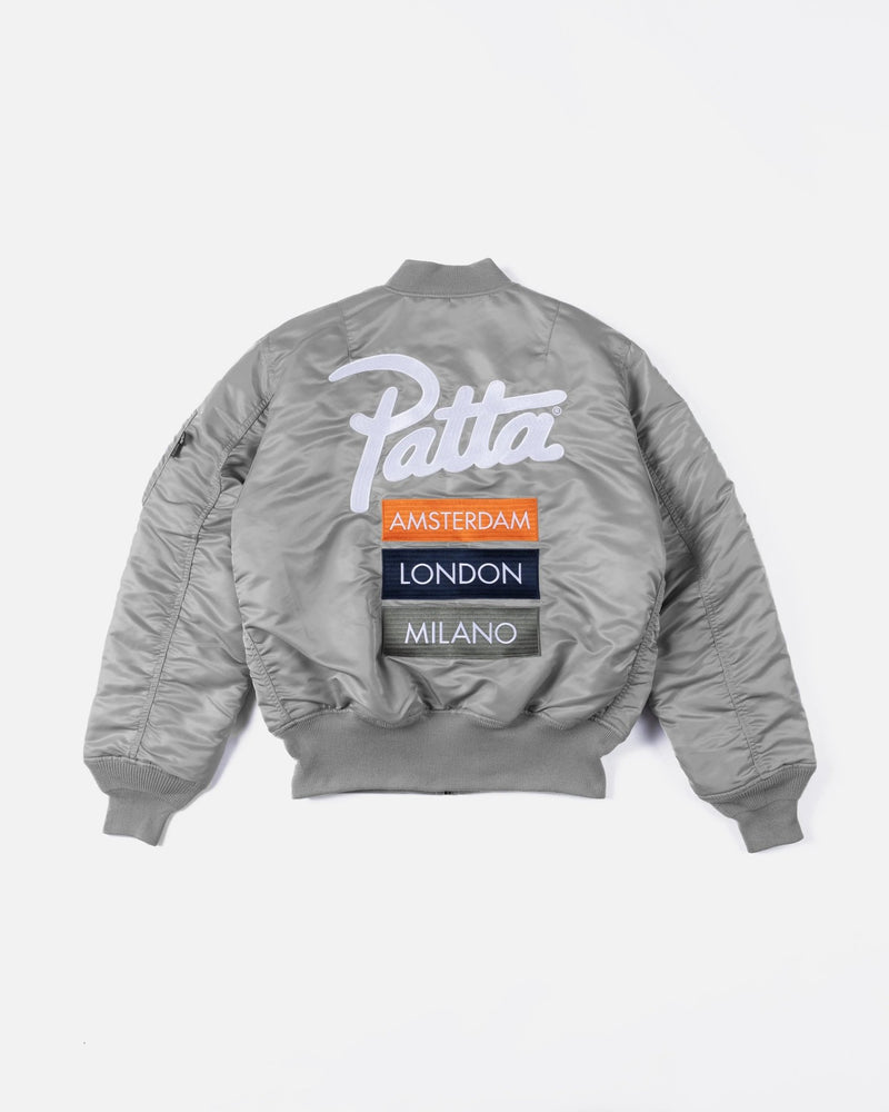 Back view of the Patta x Alpha Industries MA-1 Celebration jacket in silver featuring embroidered city patches.