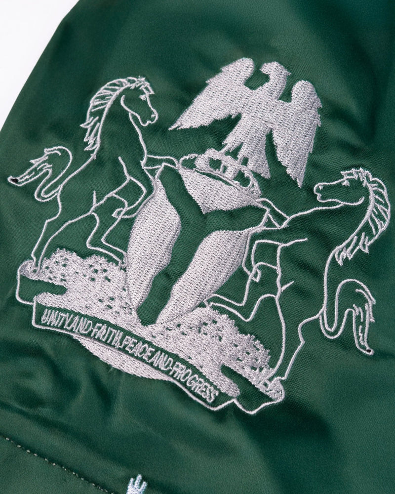 Embroidered Nigerian coat of arms on green satin Patta x Fairtex Muay Thai shorts.