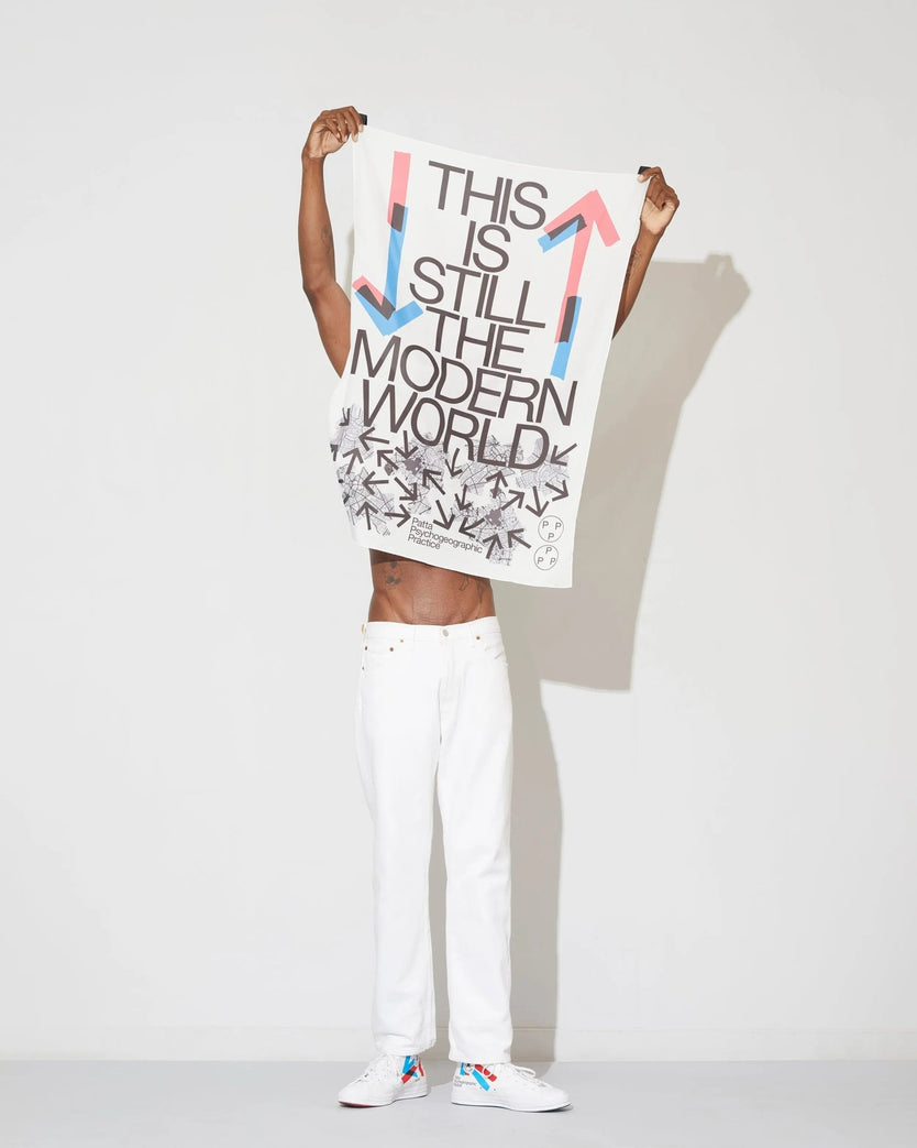 Model holding up the white Patta x Experimental Jetset graphic flag against a white studio background.