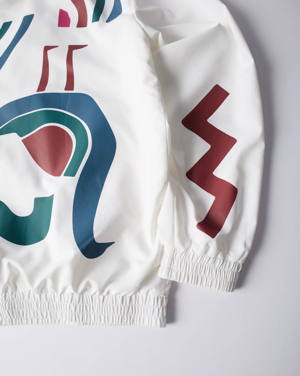 Close-up of the white byParra Tennis Maybe? Track Jacket with abstract artwork and elasticated cuffs.