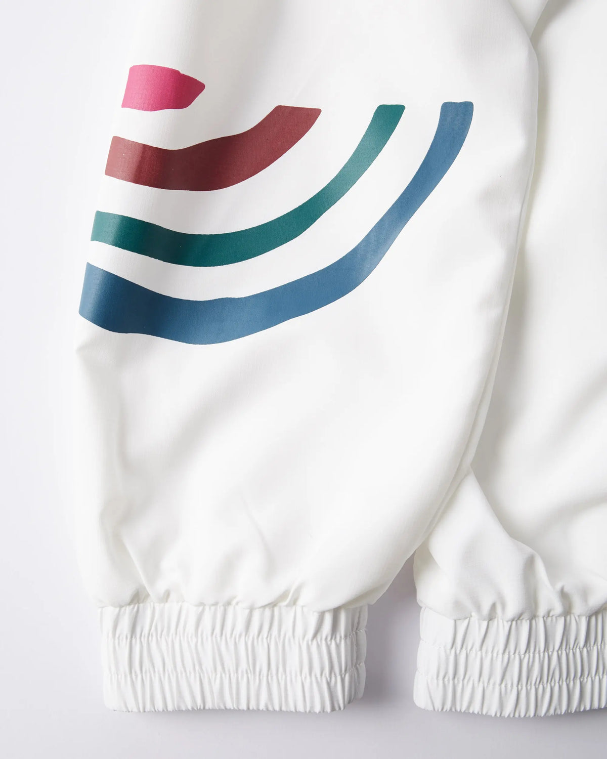 Close-up of white byParra Tennis Maybe? Track Jacket sleeve with colorful graphic stripes and elastic cuff.