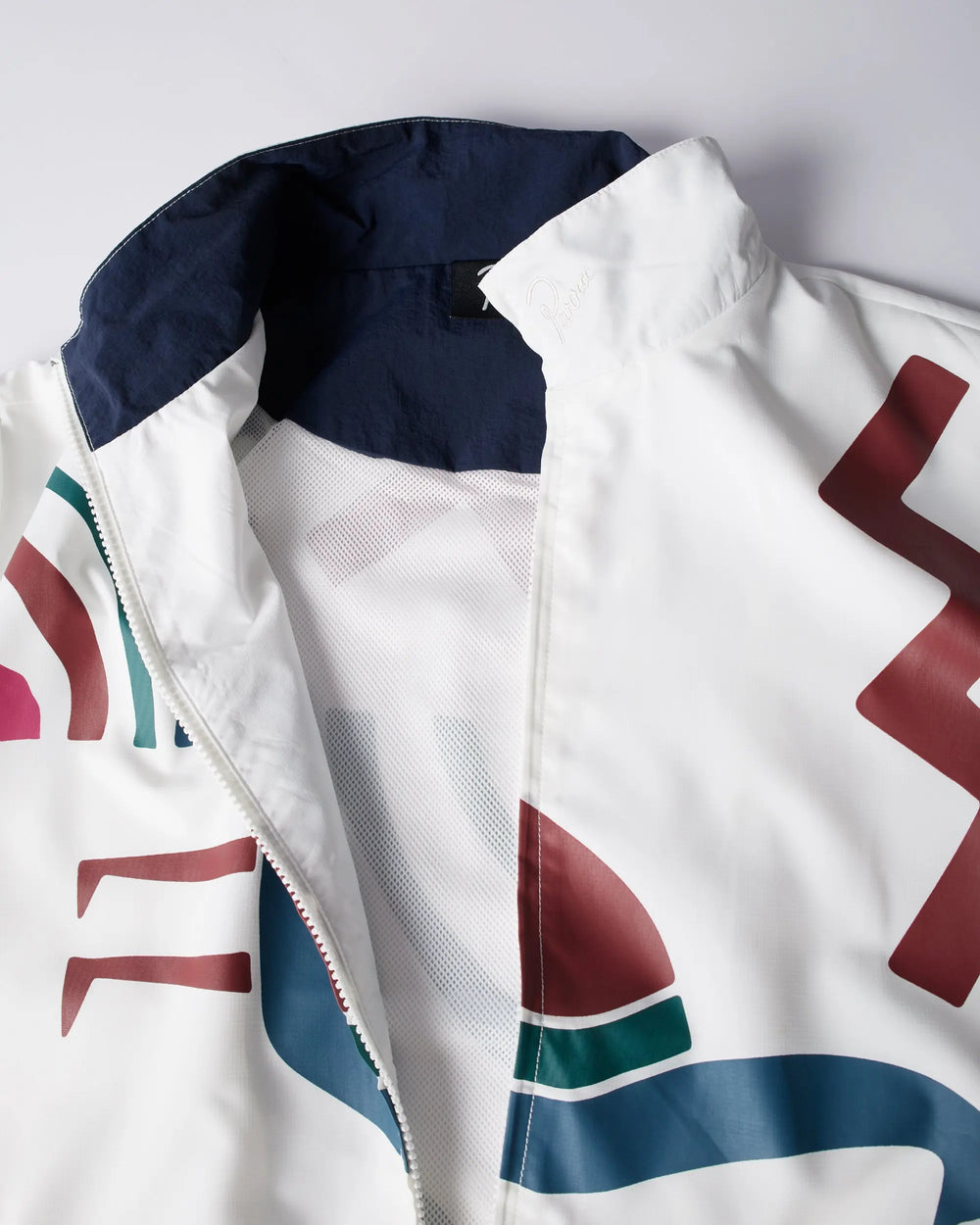 Detail of the white byParra Tennis Maybe? Track Jacket showing the collar, front zipper, and graphic print.