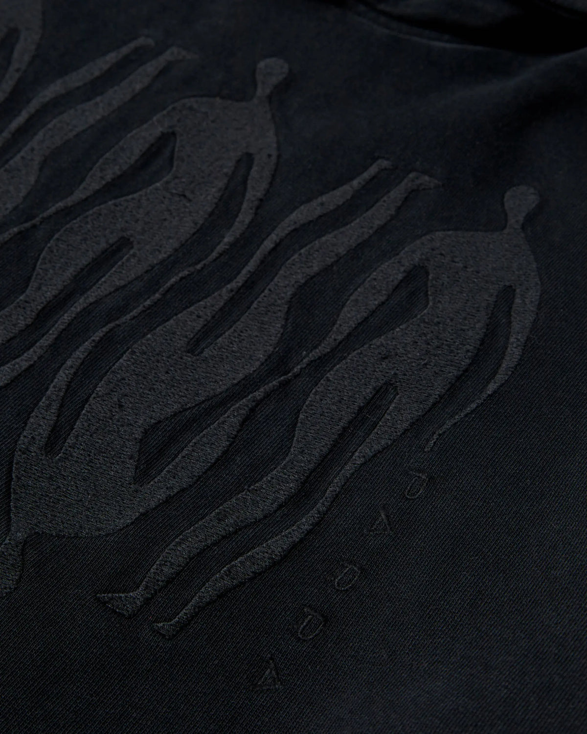 Close-up of black tonal embroidered figures on the ByParra Connected Guy hooded sweatshirt.