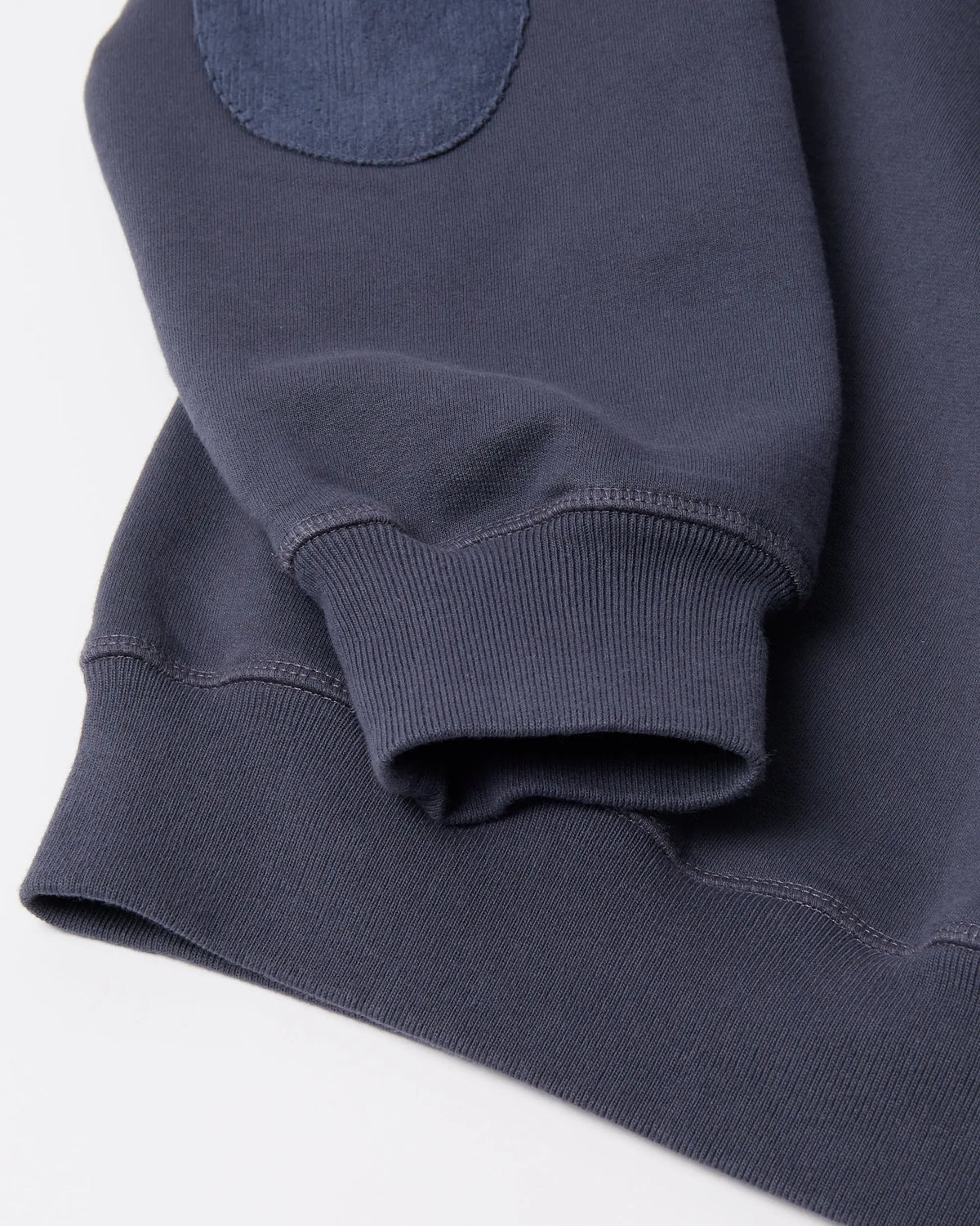 Detail of the ribbed cuff and elbow patch on a navy blue byParra Tired Champione crew neck sweatshirt.