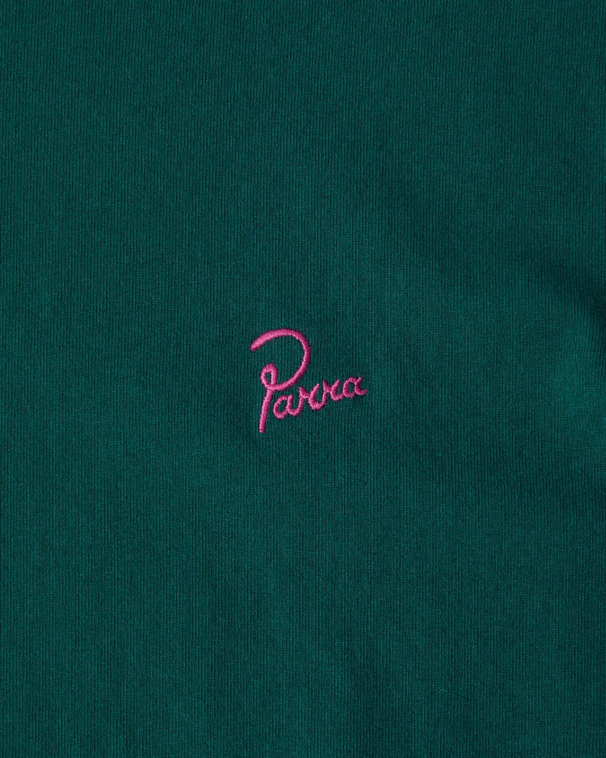 Close-up of pink embroidered Parra signature logo on a dark green cotton T-shirt.