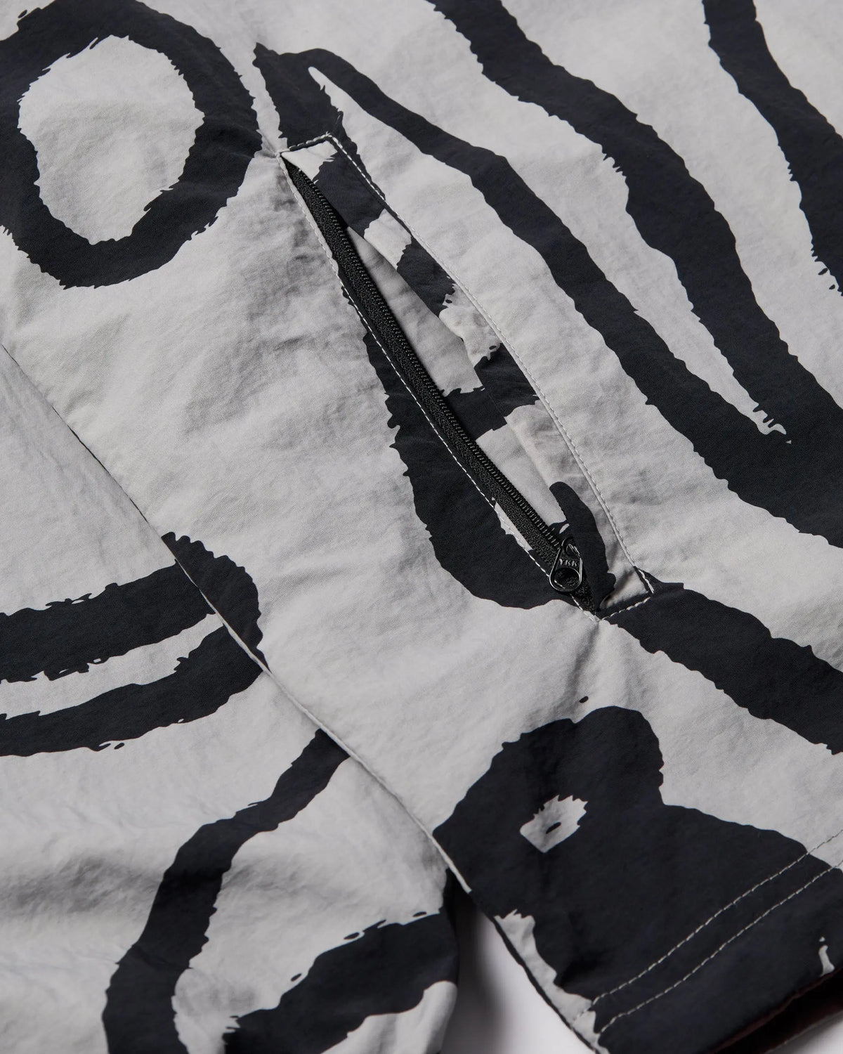 Close-up of the grey abstract print and zipper pocket on the byParra Freak Scene Reversible Track Top.