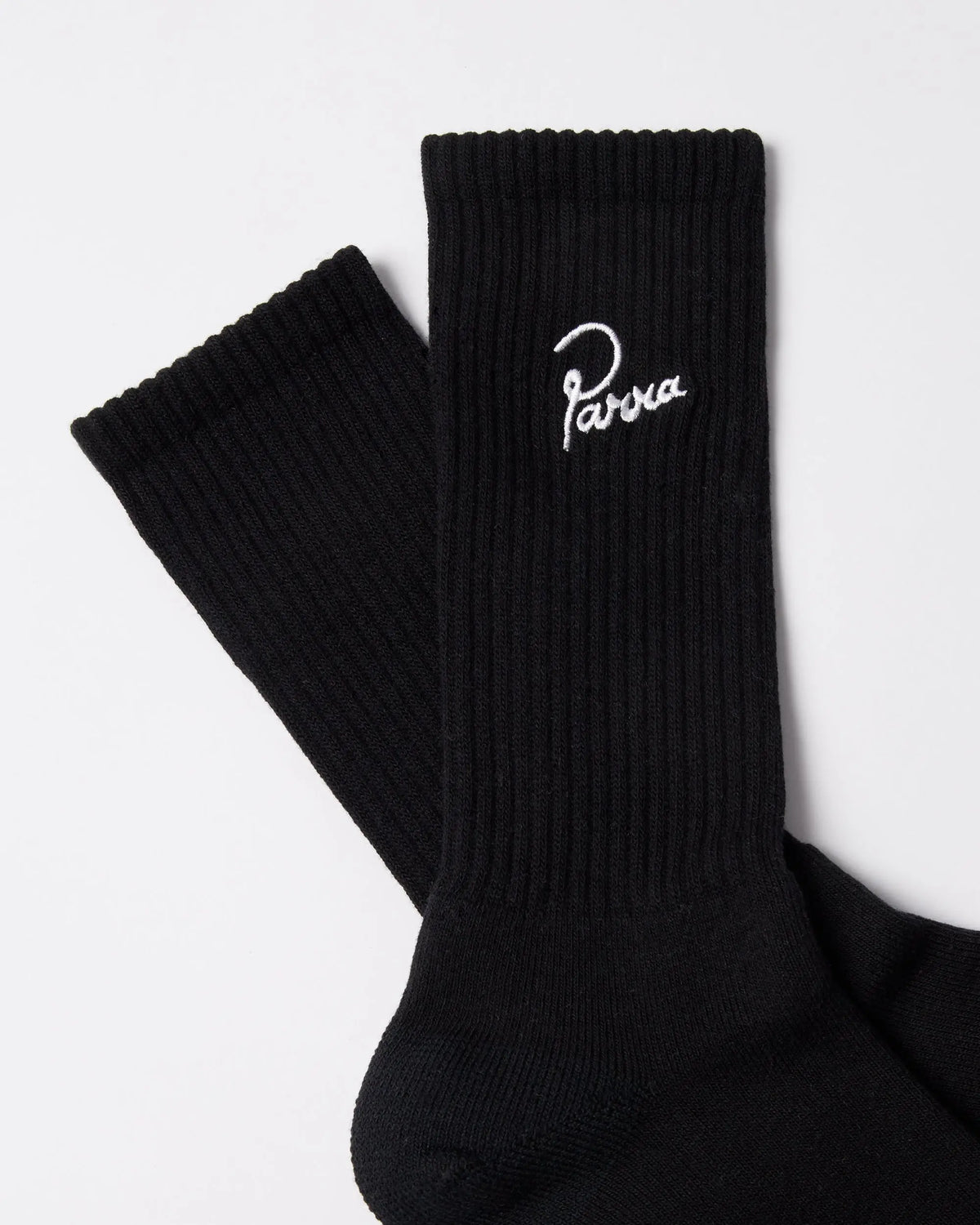 Detail view of black ribbed byParra Signature crew socks with white embroidered script logo.