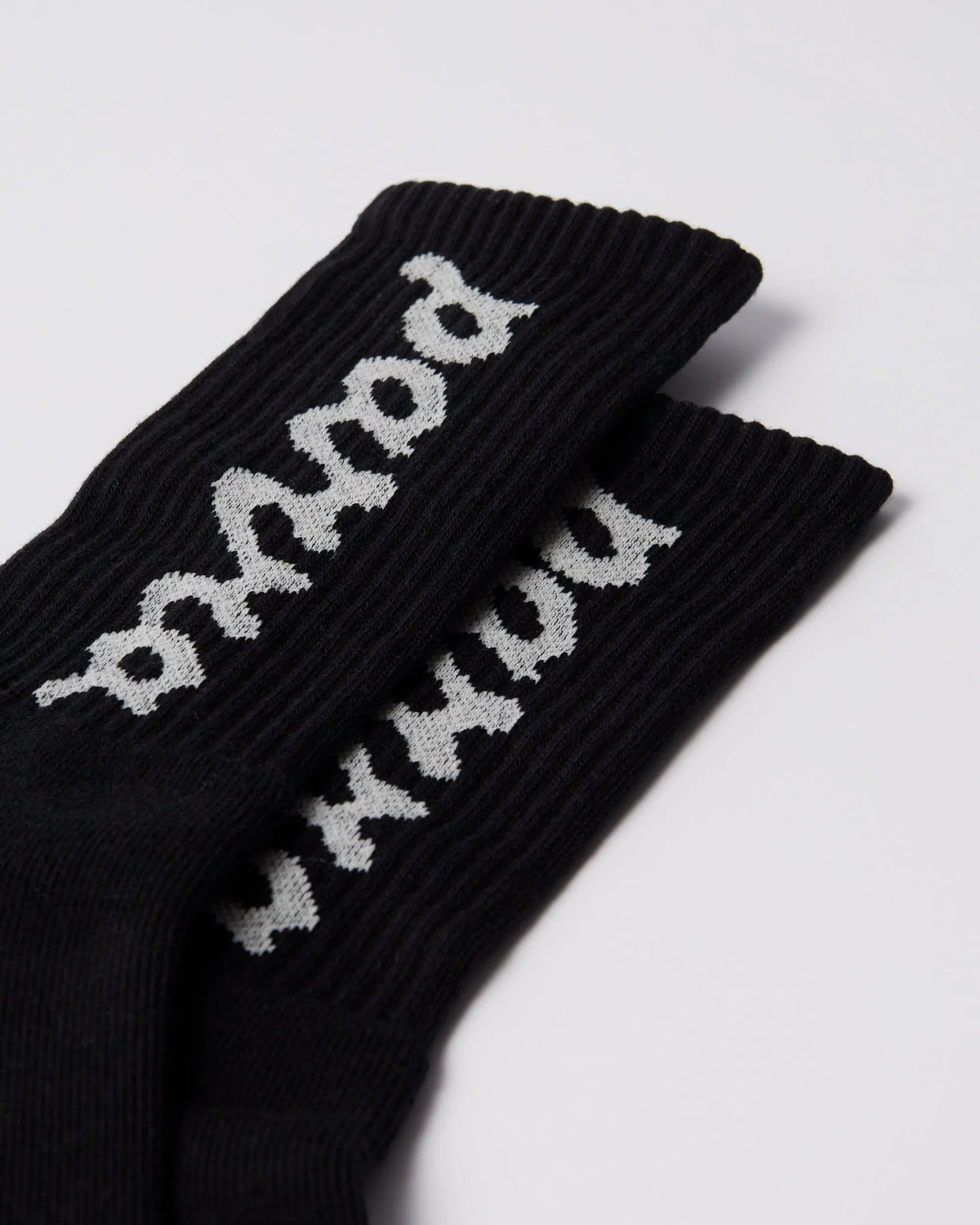 Close-up of black By Parra ribbed crew socks featuring the white lowercase script logo.