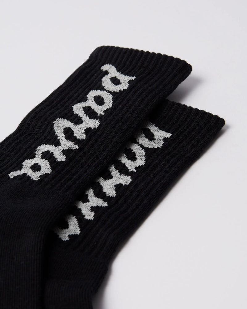 Close-up of black By Parra ribbed crew socks featuring the white lowercase script logo.