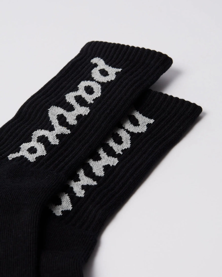 Close-up of black By Parra ribbed crew socks featuring the white lowercase script logo.