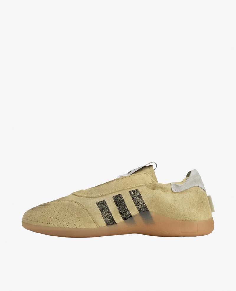 Side view of the adidas x Song For The Mute Taekwondo Mei sneaker in beige suede with black stripes and a gum sole.