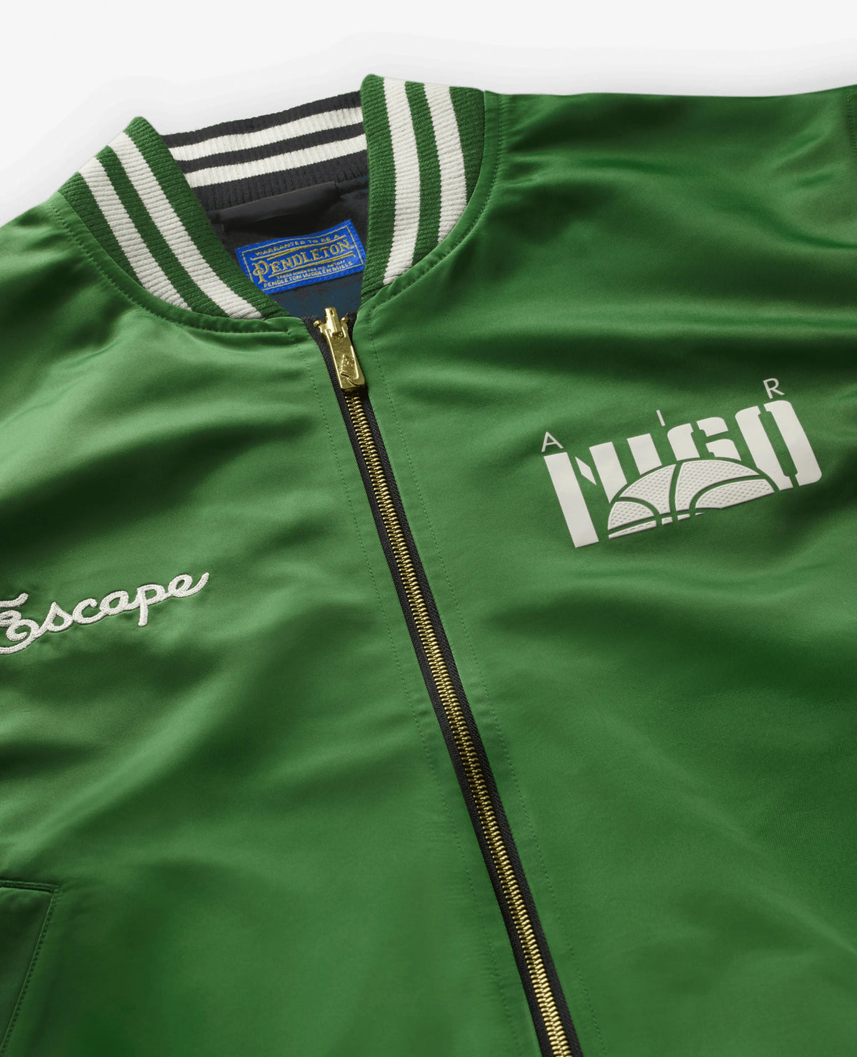 Detail of green Nike x NIGO jacket with chest logos, zip closure, and Pendleton label.