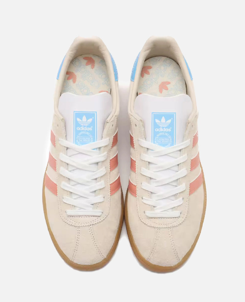 Top-down view of adidas Munchen 24 sneakers in Wonder White suede with Wonder Clay stripes and blue accents.