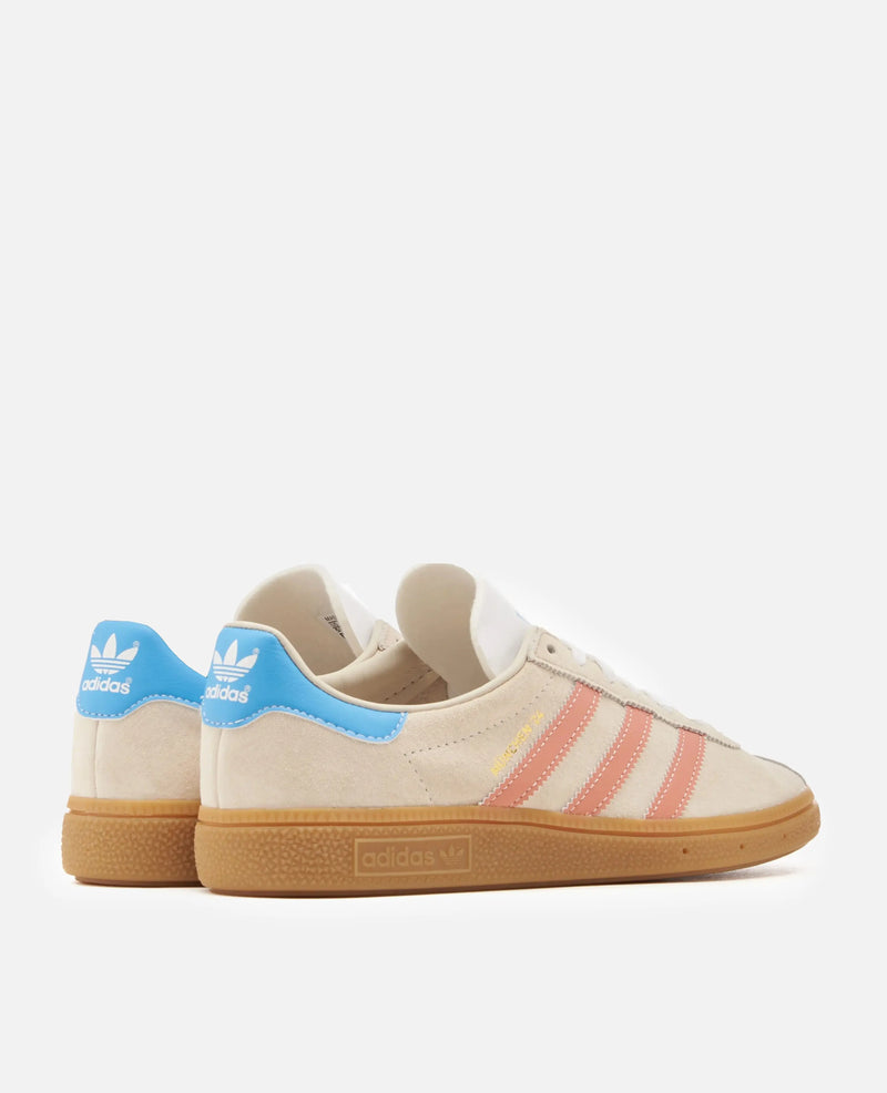 adidas Munchen 24 sneakers in Wonder White suede with clay stripes and blue heel tabs on gum soles.