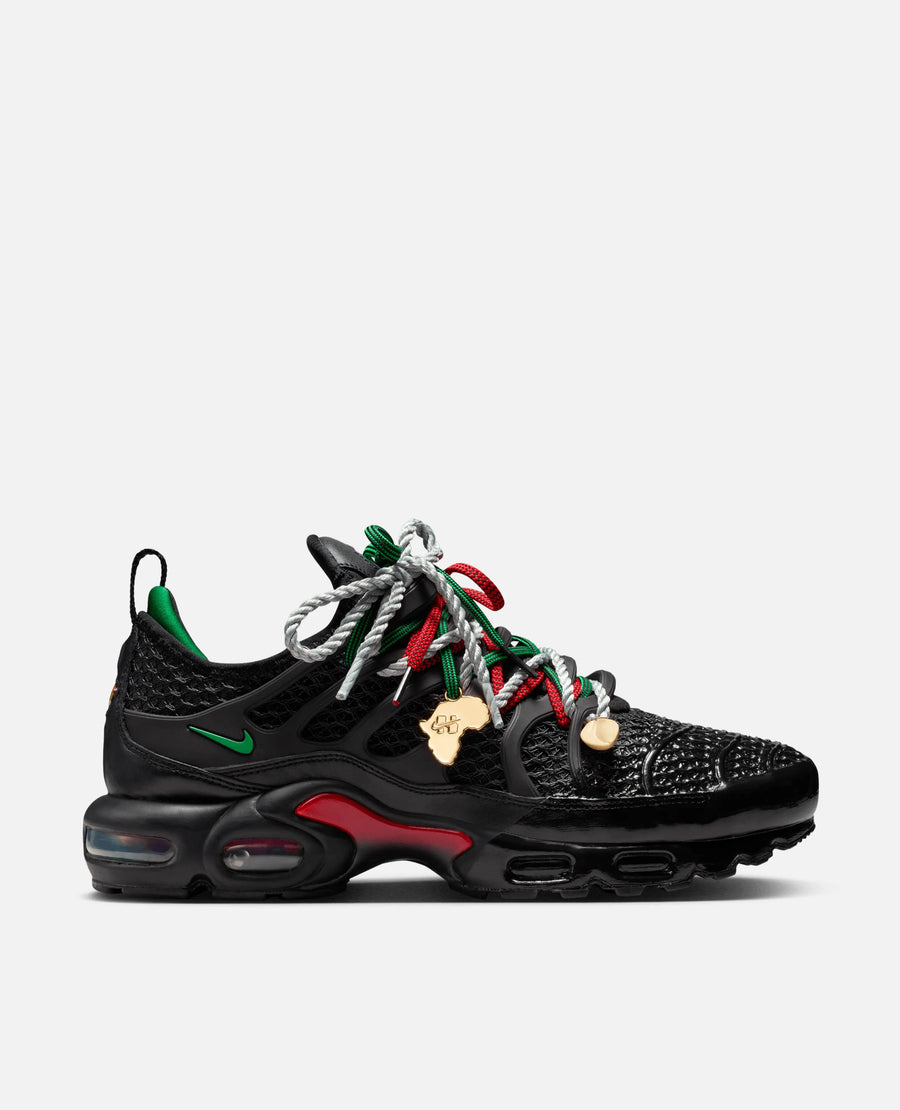 Side profile of HOMECOMING x Nike Air Max Plus in black with Pan-African red and green accents.