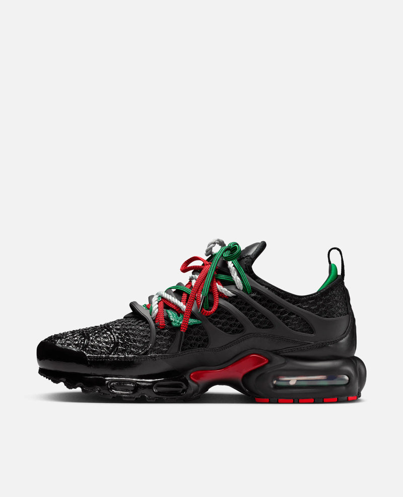 Side view of the black HOMECOMING x Nike Air Max Plus sneaker with Pan-African red and green laces.