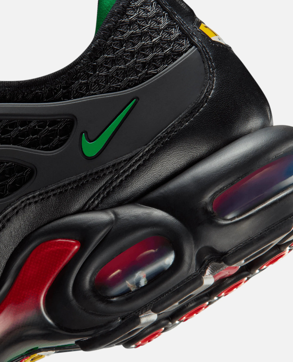 Close-up of the HOMECOMING x Nike Air Max Plus heel showing black leather, a green Swoosh, and visible Air cushioning.