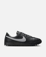 Side profile of the Nike Astrograber sneaker in Off Noir leather with a Cement Grey Swoosh.