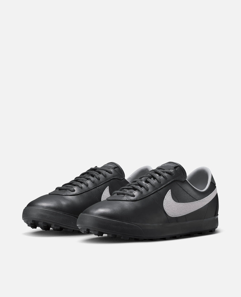 Nike Astrograbber sneakers in Off Noir black leather with Cement Grey Swooshes in a three-quarter view.