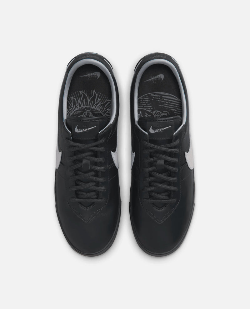 Top-down view of black leather Nike Astrograbber sneakers with cement grey accents and graphic insoles.
