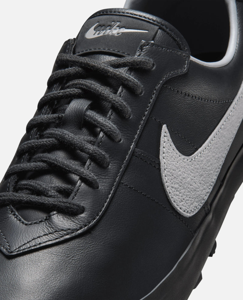 Close-up of the Nike Astrograbber in Off Noir leather with black laces and a textured Cement Grey suede Swoosh.