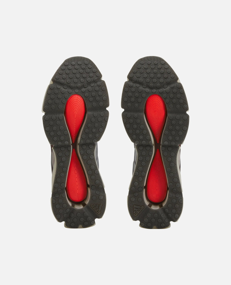 Bottom view of Adidas Chavarria Megaride sneakers showing textured black rubber outsoles with vibrant red inserts.