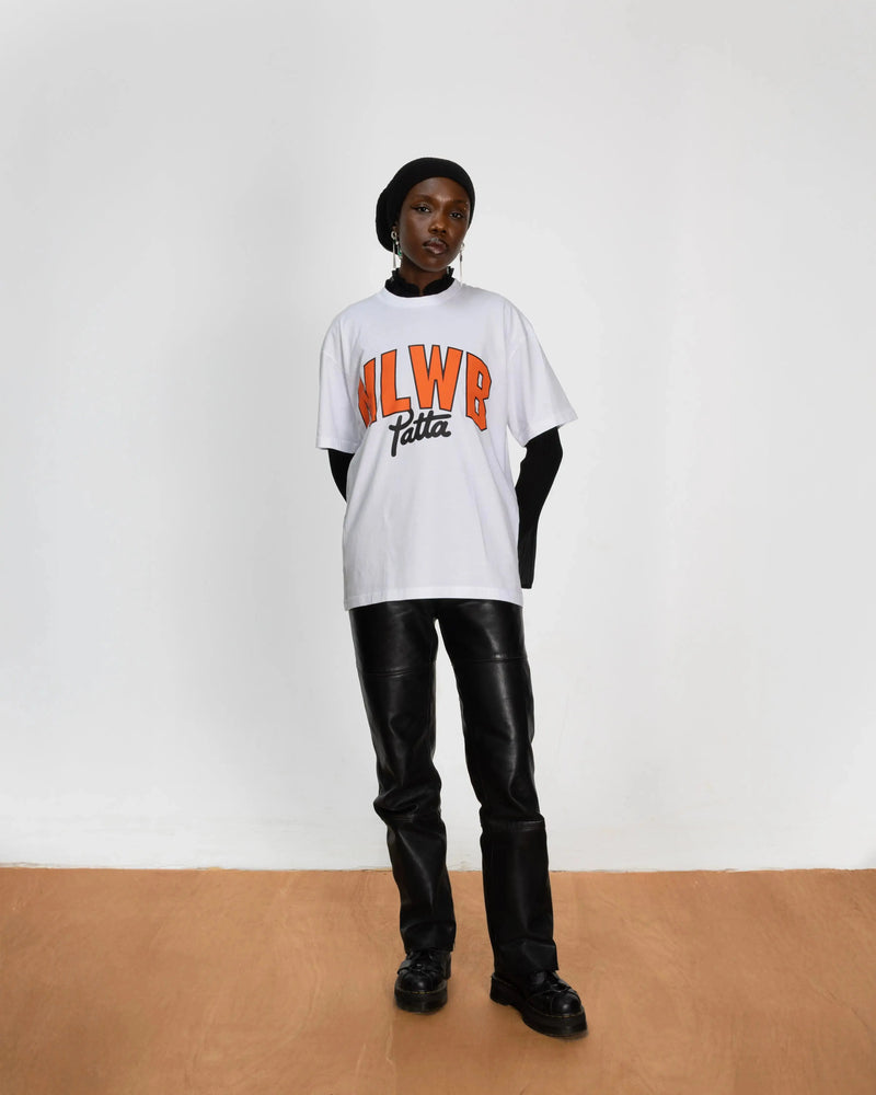 Model wearing the white Patta x NLWB 15th Anniversary T-shirt styled with black leather pants.