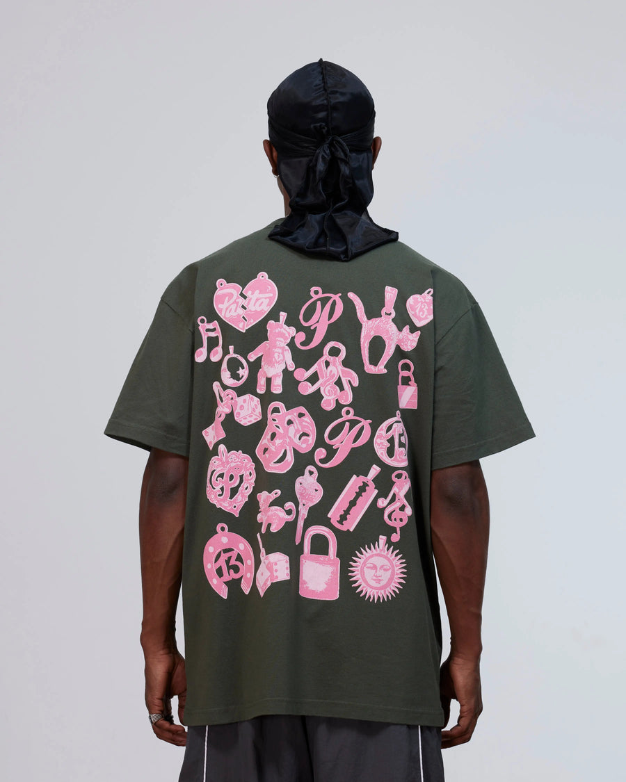 Back view of a model wearing the Patta Charm T-Shirt in climbing ivy green with pink charms artwork.
