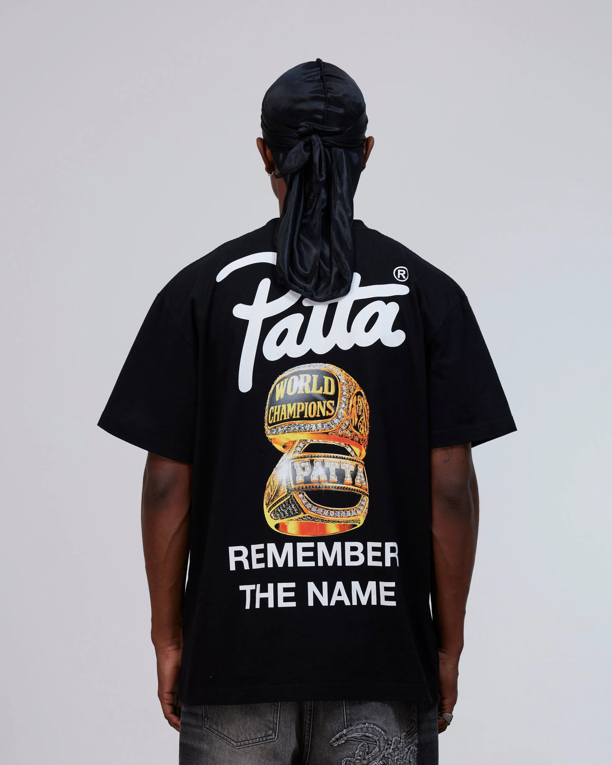 Back view of a model wearing the black cotton Patta Championship T-Shirt with graphic artwork.