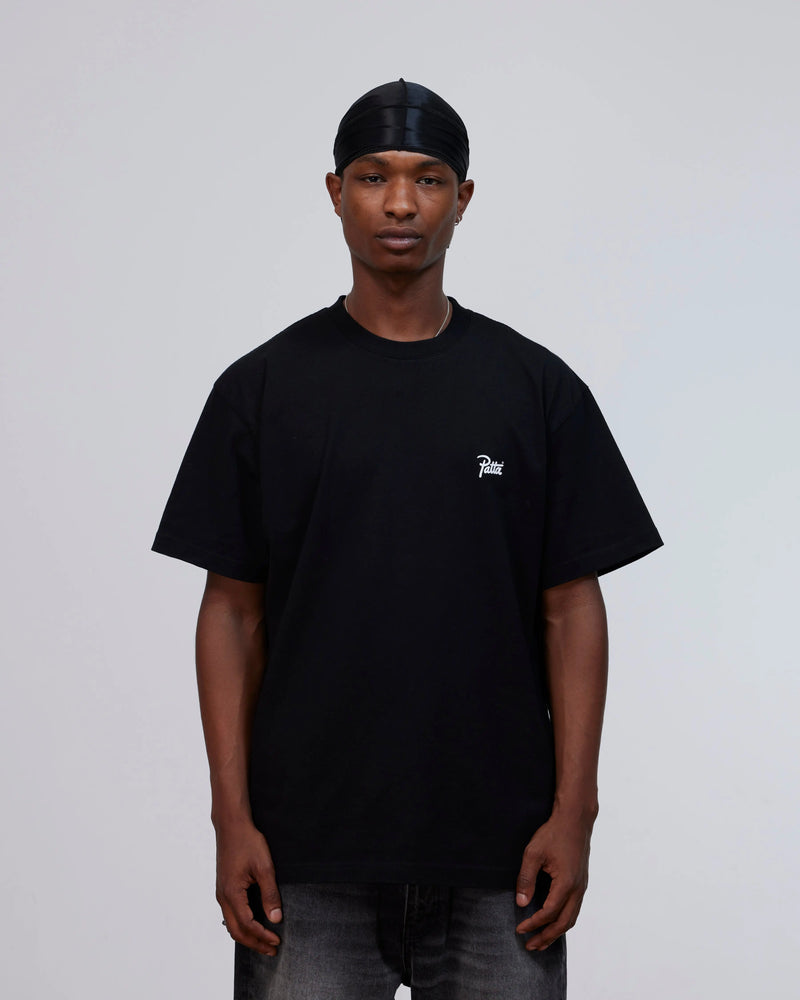 Model wearing the black Patta Championship cotton T-shirt with a white script logo on the chest.