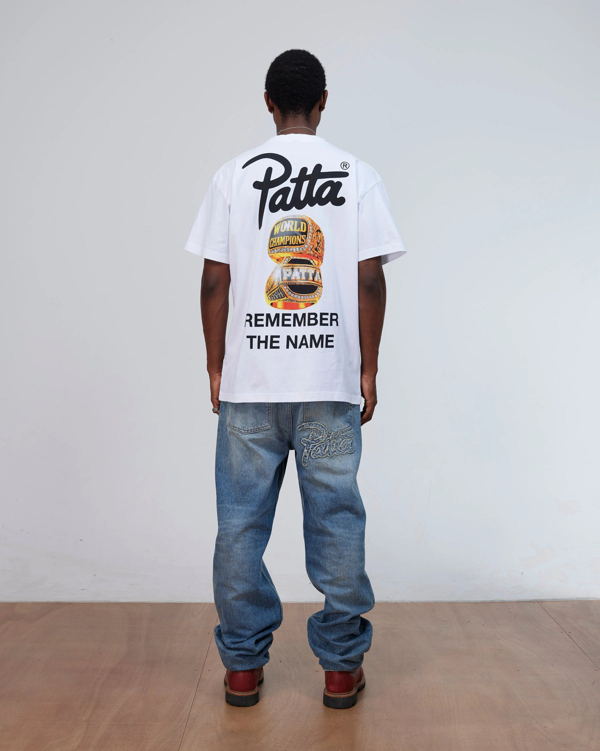 Back view of a model wearing the white Patta Championship T-Shirt with Remember The Name graphic.