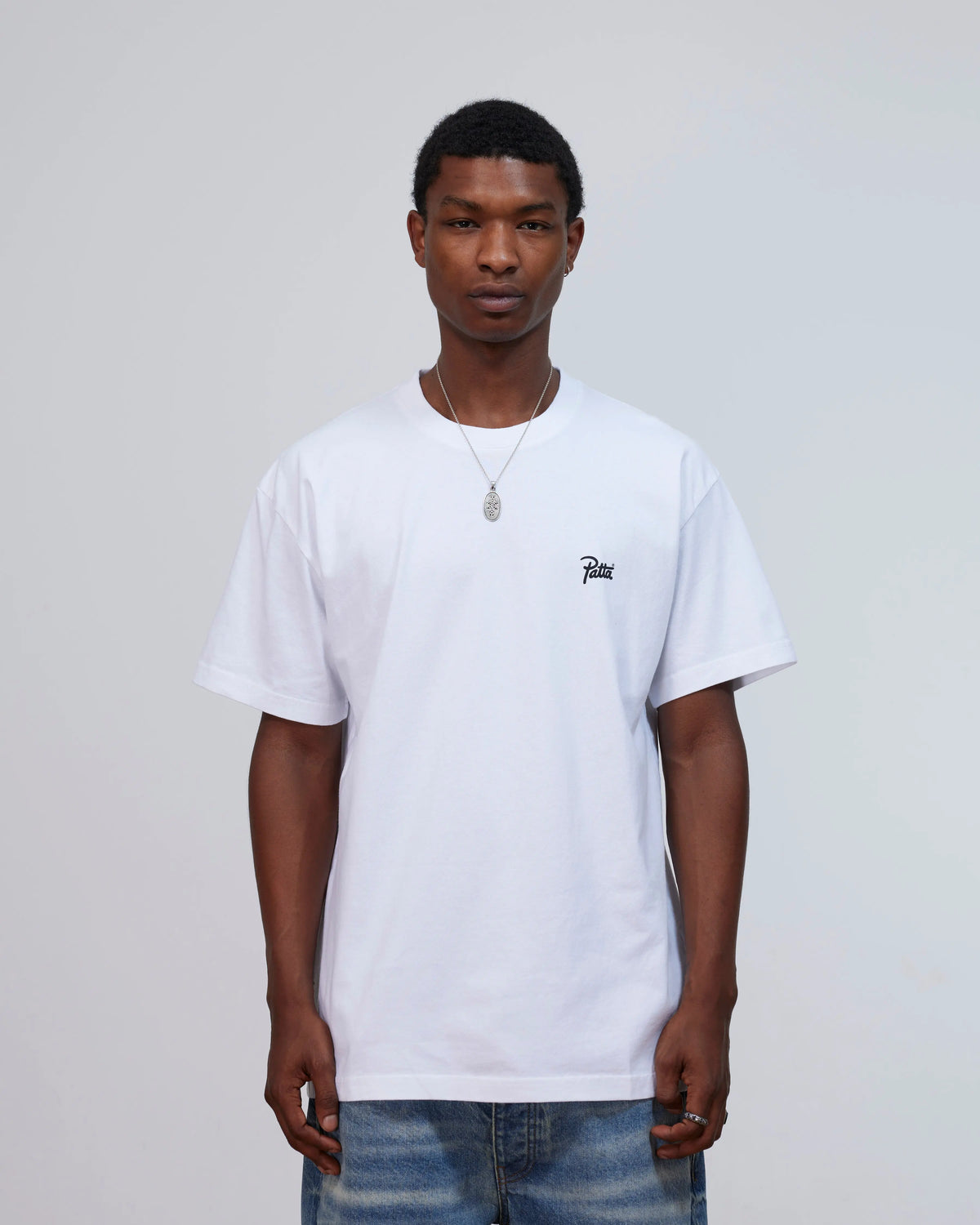 Model wearing the white Patta Championship T-shirt featuring a script logo on the chest.
