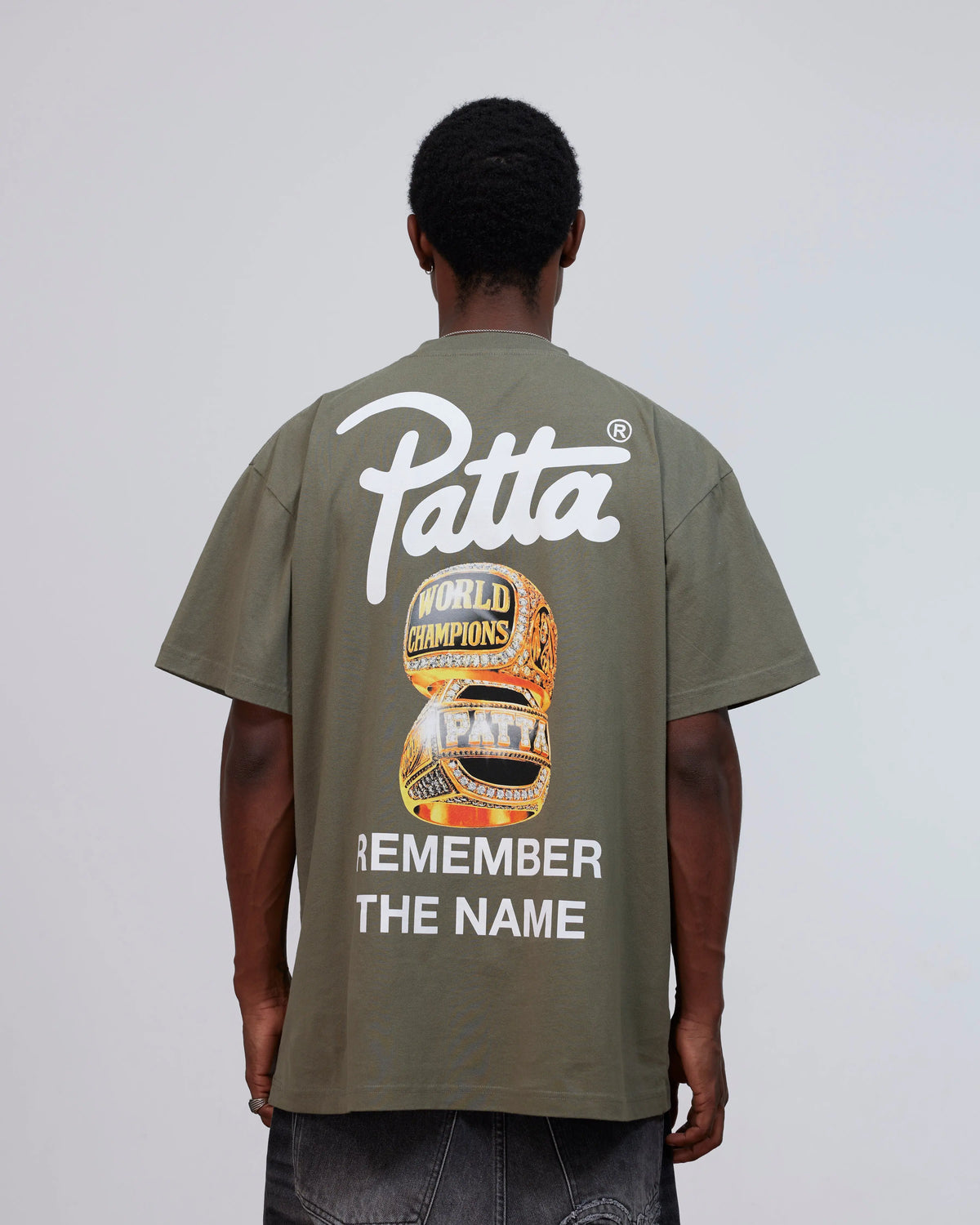 Back view of model wearing the Patta Championship T-Shirt in dusty olive with graphic print.