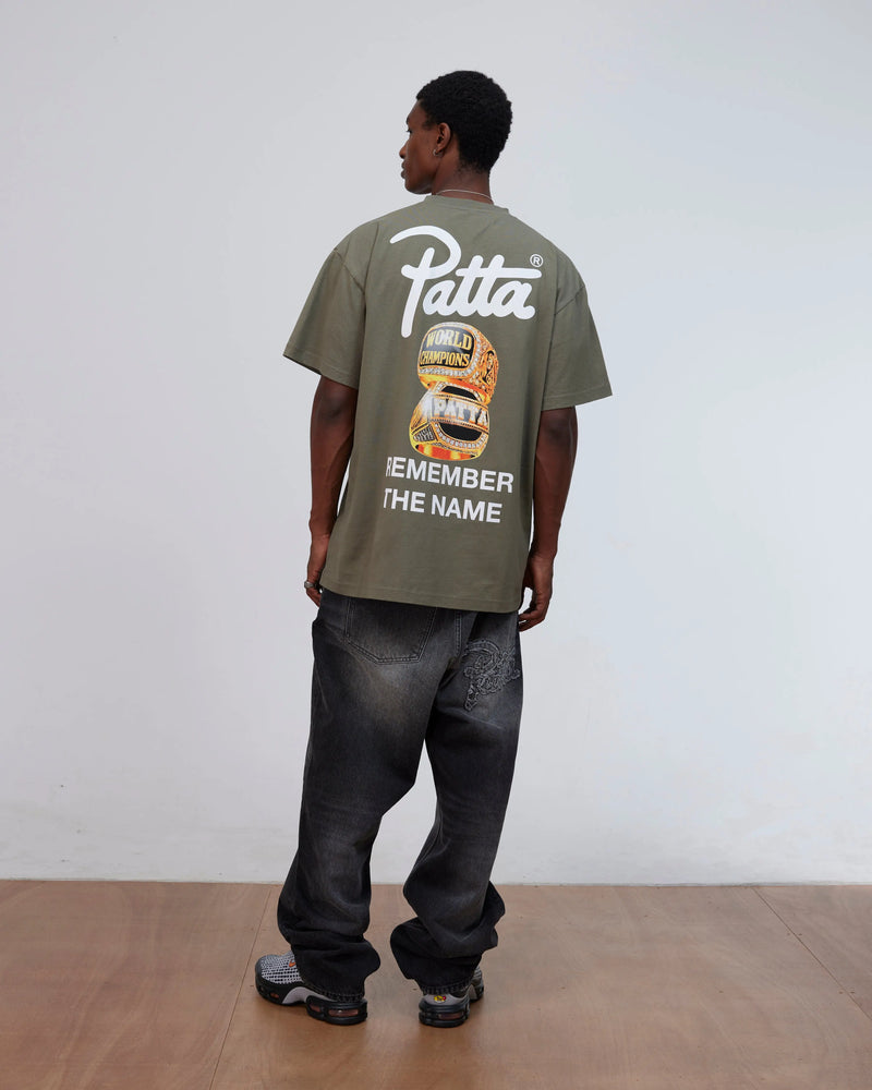 Back view of a model wearing the Patta Championship T-Shirt in dusty olive with back graphic print.