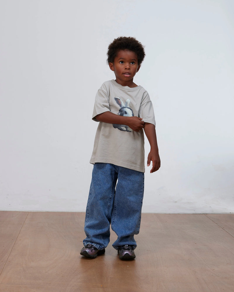Young boy wearing the flint gray Patta Kids Bunny T-Shirt and loose denim jeans.