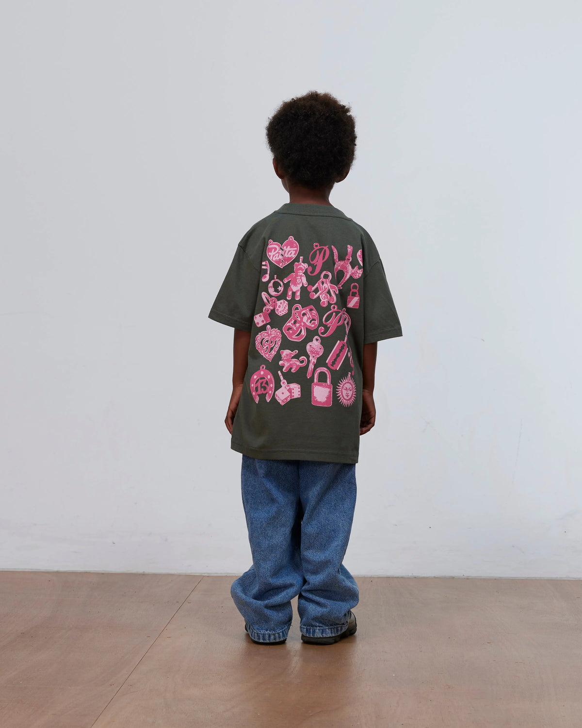 Back view of a kid wearing the green Patta Kids Charm T-Shirt with pink charms print.