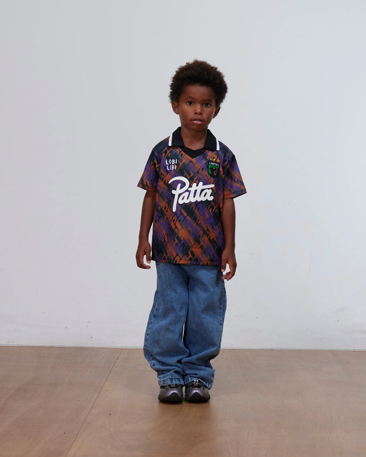 Young boy wearing the Patta Kids All Over P Football Jersey in pansy with baggy denim jeans.