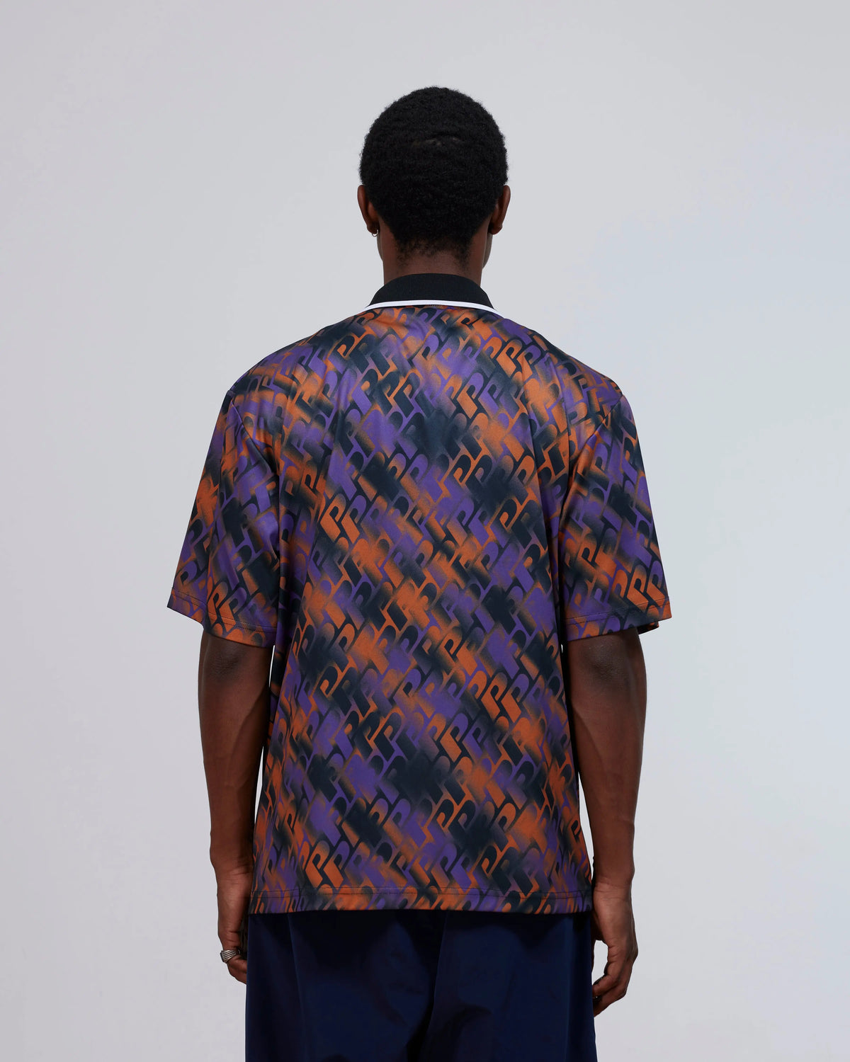 Back view of a model wearing the Patta All Over P Football Jersey in Pansy purple and orange.