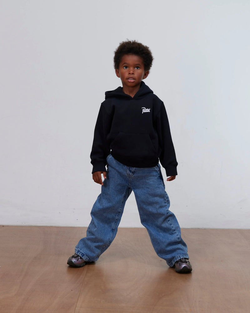 Young boy wearing the black Patta Kids Championship hooded sweater and blue jeans.