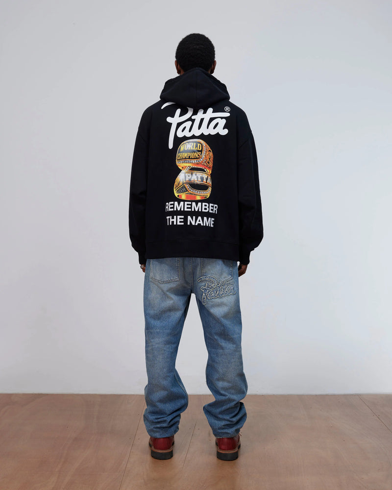 Back view of a model wearing the black Patta Championship Hooded Sweater with back graphic print.
