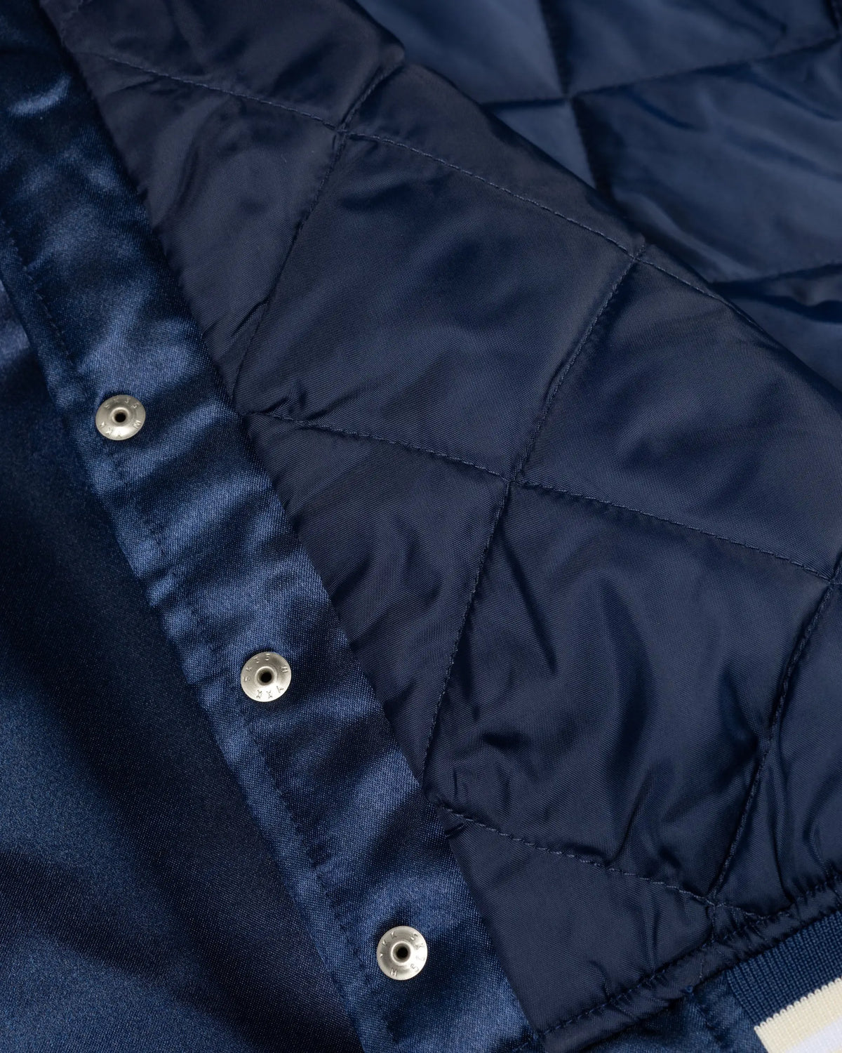 Close-up of the quilted lining and snap buttons on the Patta Kids Satin Bomber Jacket in Black Iris.