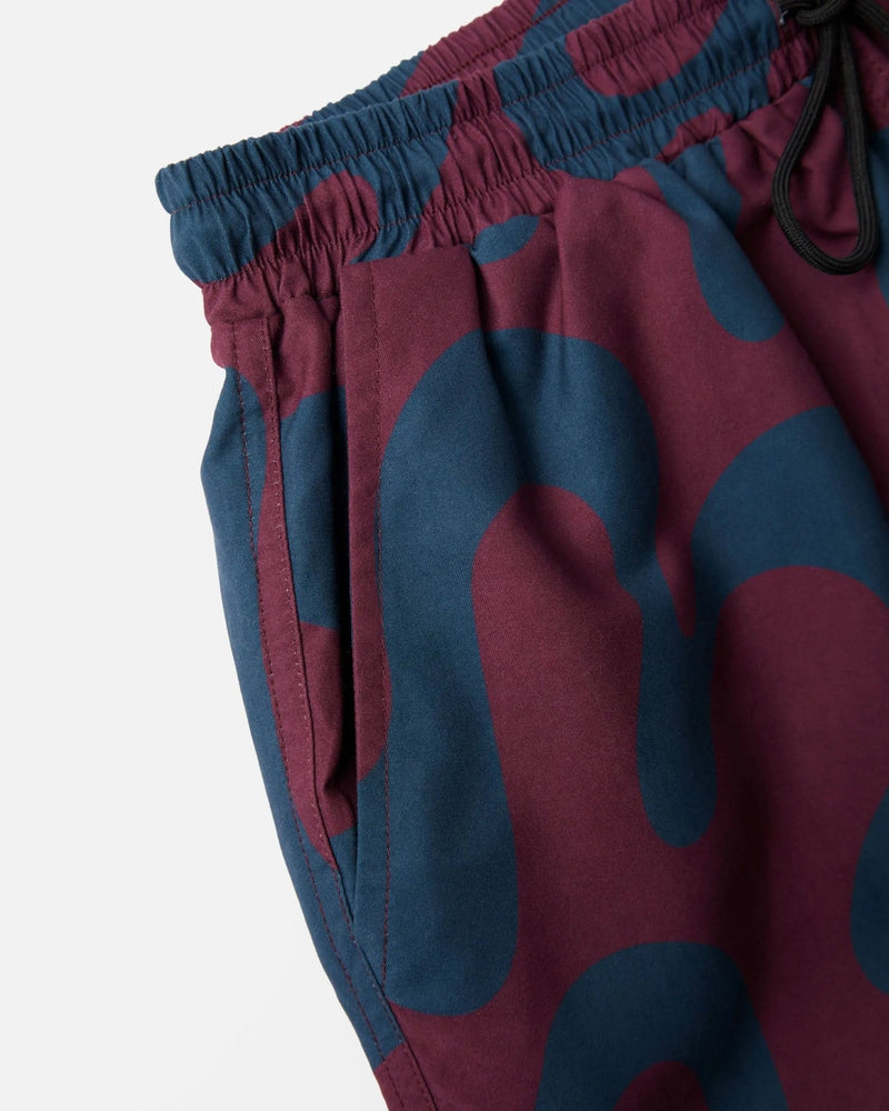 Close-up of ByParra Splashed Swim Shorts in burgundy showing the elastic waistband and side pocket.