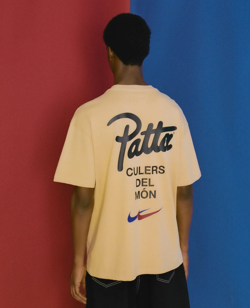 Back view of model wearing sesame FCB x Patta Culers del Món t-shirt with logo print.