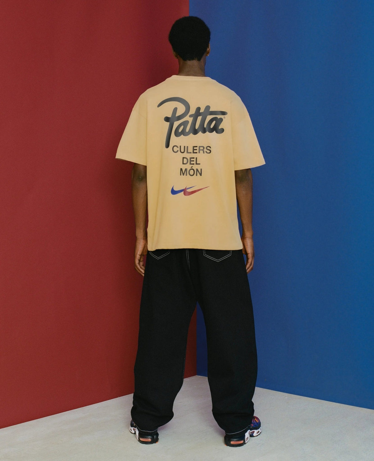 Back view of a model wearing the sesame FCB x Patta Culers del Món graphic T-shirt.