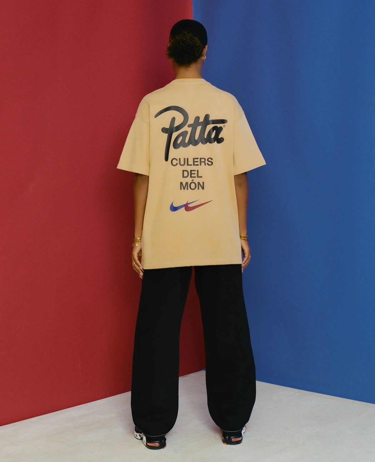 Back view of model wearing the sesame FCB x Patta Culers del Món T-shirt with graphic branding.