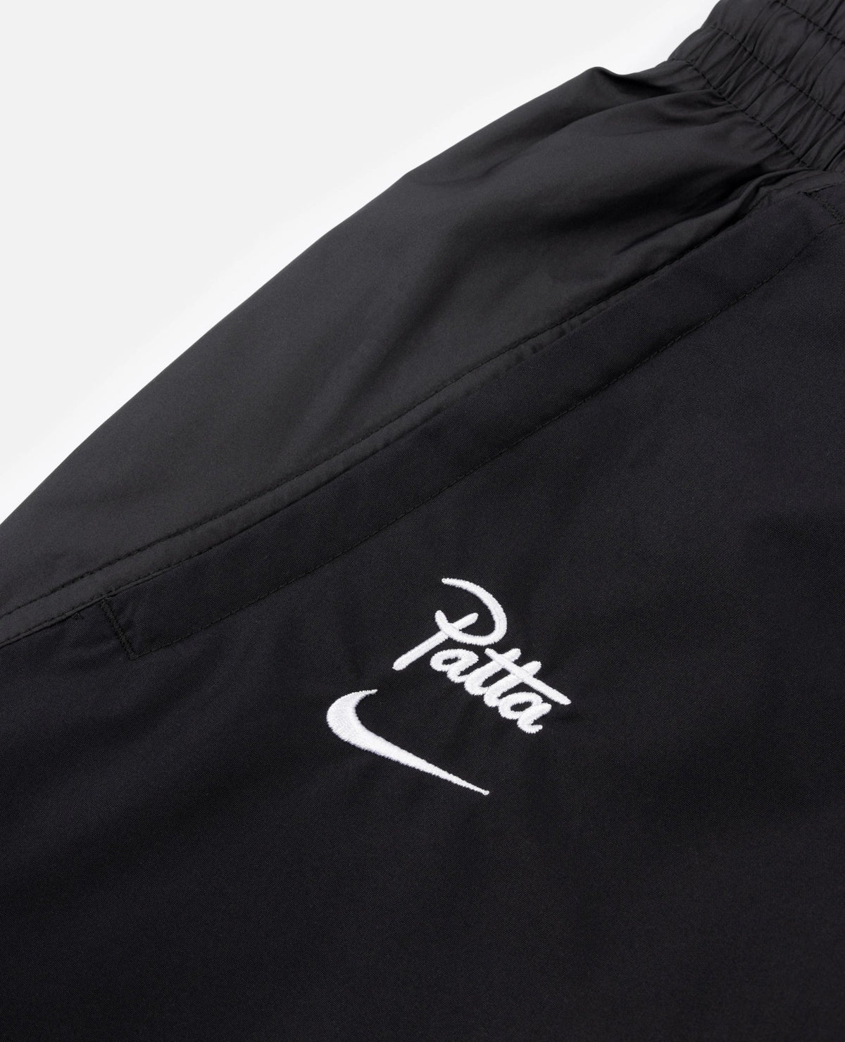 White embroidered Patta logo and Nike swoosh on black FCB x Patta Culers del Món track pants.
