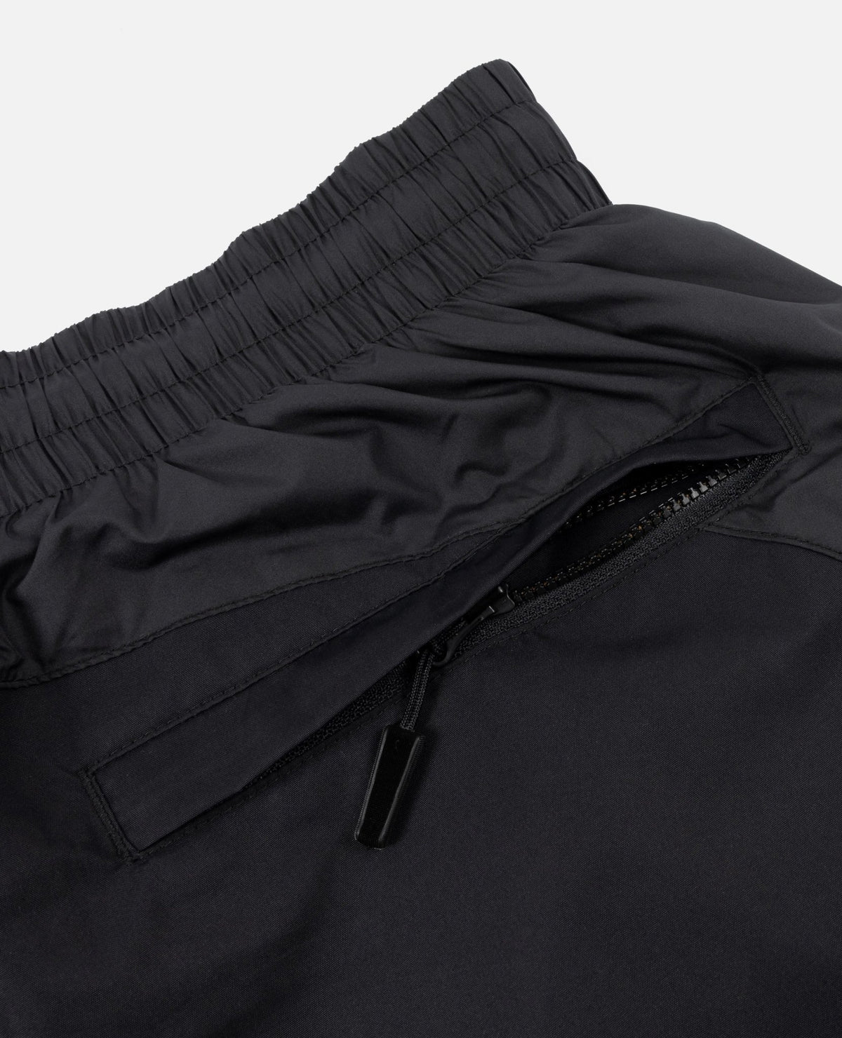 Close-up of the zippered pocket and elastic waistband on the FCB x Patta Culers del Món Track Pants in black.